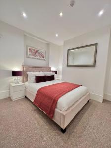 a bedroom with a large bed with a red blanket at Modern South Kensington Apartment in London