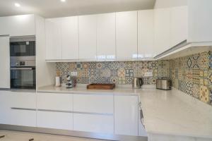 a white kitchen with white cabinets and tiles at Casa SP- Villa with heated pool near Vilamoura, Vale do Lobo in Quarteira
