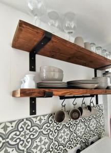 a kitchen shelf with plates and utensils on it at Driftwood Apartment in Saltburn-by-the-Sea