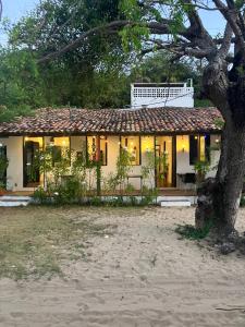 uma casa com uma árvore em frente em Mangue Seco Lodge - Experiência Gastronômica em Mangue Sêco