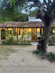 una casa con un árbol delante de ella en Mangue Seco Lodge - Experiência Gastronômica en Mangue Sêco