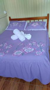 Una cama púrpura con dos rollos de toallas. en Pousada Flor da Serra en Urubici