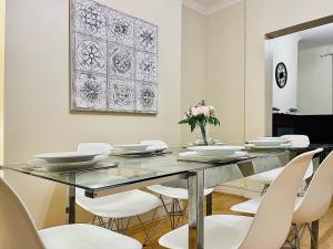 a dining room with a glass table and white chairs at Alice's Place in London