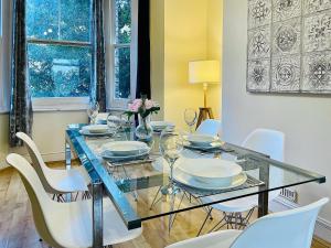 a dining room with a glass table and white chairs at Alice's Place in London