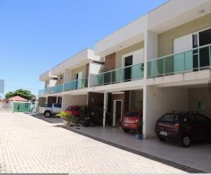 un edificio con dos coches estacionados en un estacionamiento en Sobrado super lindo a duas quadras praia., en Guaratuba