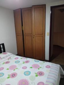 a bedroom with a bed with a floral comforter at Habitaciones en Edificio Ginebra Manizales in La Linda