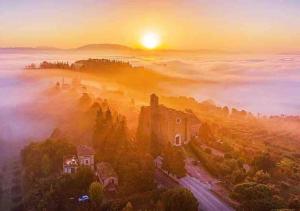Ein nebliger Sonnenaufgang über einer Stadt mit einem Schloss inmitten eines Hügels. in der Unterkunft Depandance holiday Villa, garden and privat pargking in Perugia