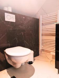 a bathroom with a toilet and a black wall at Le Beau Séjour 1 - Très Elégant - Proche Aéroport in Beauvais