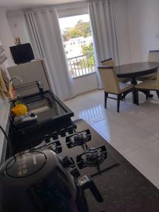 a kitchen with a stove and a dining room with a table at Ótimo Apartamento São Lourenço in São Lourenço