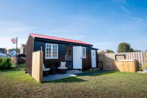 um pequeno barracão com duas casas de banho num quintal em The Other Red Hut em Rye Harbour