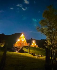 un grande fienile illuminato di notte in un campo di Glamping La Herradura a Santa Rosa de Cabal