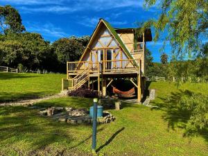 a house with a deck on a green field at Glamping La Herradura in Santa Rosa de Cabal