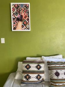 uma imagem pendurada numa parede verde acima de uma cama em Cas-zaa em Teotitlán del Valle