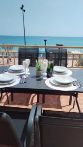 a table with plates and a bottle of wine and the ocean at Luxury beachfront, free private parking in Fuengirola