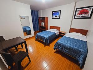 Habitación de hotel con 2 camas y escritorio en HOSTAL VEGA'S NAZCA en Nazca