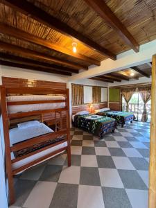a room with three bunk beds and a checkered floor at Victor Hugo Hotel in Puerto López