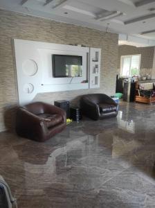 uma sala de estar com duas cadeiras de couro e uma televisão em maison spacieuse et lumineuse em Hammamet Sud