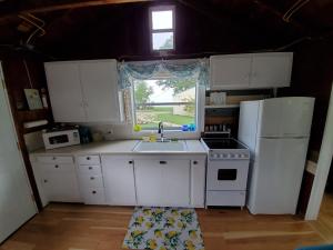 een keuken met witte kasten, een wastafel en een raam bij LemonDrop Lake-Front Cottage in Madison