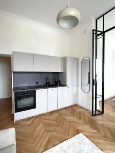 a kitchen with white cabinets and a wooden floor at Old Town Residence , Wi-fi , 2-Beds , Aesthetics - by HIK Apartments in Warsaw