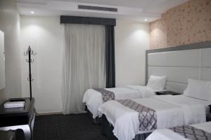 a hotel room with three beds with white sheets at Shouel Inn Furnished Apartments in Makkah