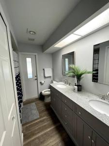 a bathroom with two sinks and a toilet and a mirror at New! Fully Renovated 3/2 Luxury Vacation Home in Venice