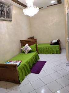 a bedroom with two green beds and a chandelier at Jinane in Meknès