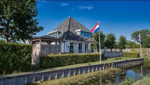 una casa con una bandiera e un cartello di fronte a un fiume di Cozy Chalet in Camping 't Venhop a Berkhout