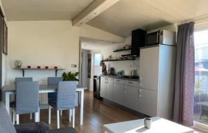 a kitchen with a white refrigerator and a table with chairs at Cozy Chalet in Camping 't Venhop in Berkhout