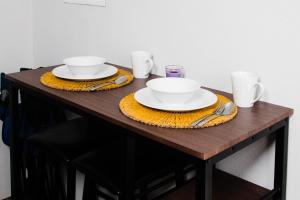 a wooden table with two plates and bowls on it at Flora Fauna 84 Aruba Apartment in Palm-Eagle Beach