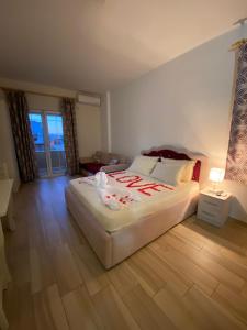 a bedroom with a large white bed and wooden floors at Hotel Vila Dedej in Durrës