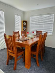 a wooden dining room table with four chairs at Papamoa B&B in Papamoa