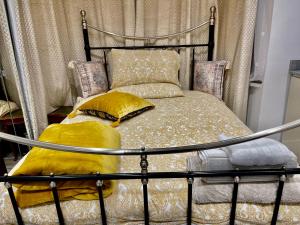 1 cama con marco de metal y almohadas amarillas en Luxury 6 Bedroom House, all with En-suite bathroom - West London - Wembley Stadium, OVO Arena 5 km, en Greenford