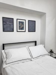a bedroom with a white bed with three pictures on the wall at 'TheFive' Camden Town in London