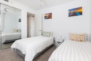 a white bedroom with two beds and a mirror at Solaris 312 in Forster +18 photos
