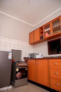 uma cozinha com armários de madeira e um frigorífico em Macky cottages em Kampala
