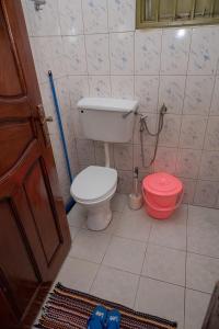 uma casa de banho com um WC e um balde vermelho em Macky cottages em Kampala