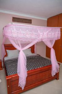 uma cama de dossel num quarto em Macky cottages em Kampala
