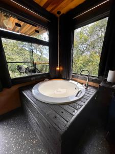 a bath tub in a room with two windows at Casa Container 80 in Campos do Jordão