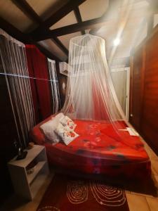 a bedroom with a red bed with a net at Villa le flamboyant in Le Marin