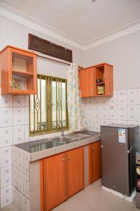 uma cozinha com armários de madeira e um frigorífico de aço inoxidável em Macky cottages em Kampala