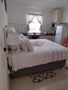a bedroom with a bed with white sheets and a refrigerator at 4 Centenary Road Ixopo in Ixopo