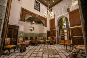 a room with a couch and chairs and a chandelier at Dar Usham Fes Luxury Guest House in Fès