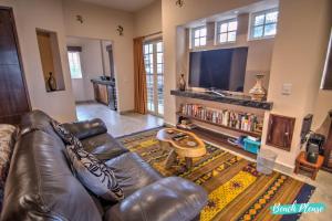 a living room with a leather couch and a television at Casa Colibri - Private Beachfront Oasis in Cruz de Huanacaxtle