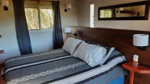 een bed in een kamer met een spiegel en een raam bij Nairandey in La Pedrera