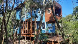 a blue house with a deck in the woods at Nairandey in La Pedrera