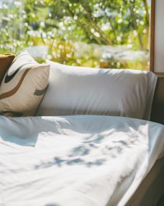 a bed with white sheets and pillows next to a window at Stay Maeumgyul - Aewol Jacuzzi Pension in Jeju