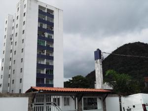 a tall white building next to a building at Ap aconchegante 12 min a pé p Praia in Praia Grande