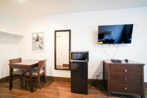 een woonkamer met een tafel en een televisie en een tafel en stoel bij SIGNAL HILL MOTEL BEACH MOTEL in Long Beach