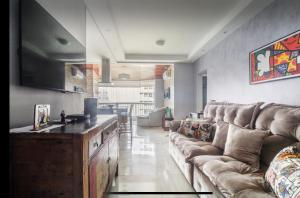 a living room with a couch and a television at Flat botique Guarujá in Guarujá