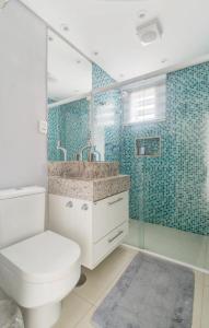 a bathroom with a toilet and a glass shower at Flat botique Guarujá in Guarujá